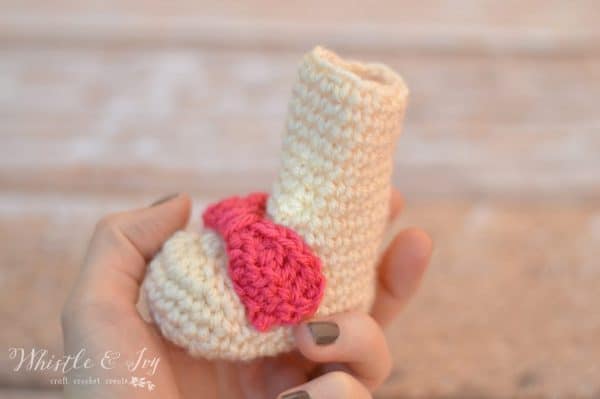 hand holding small crochet newborn booties for baby 