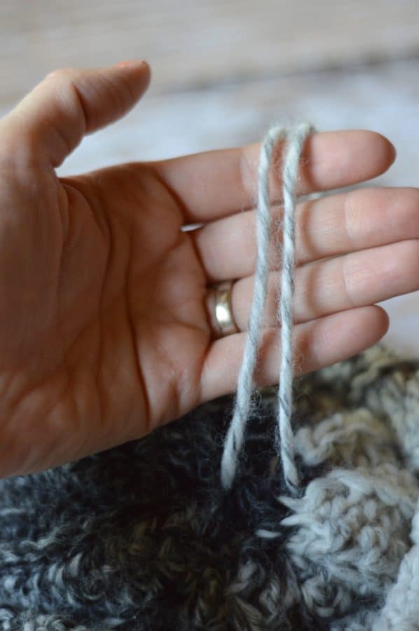 hand holding two strands of yarn 