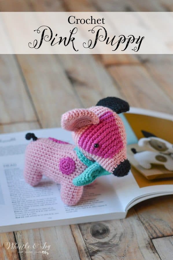 crochet pink puppy sitting on a crochet book 
