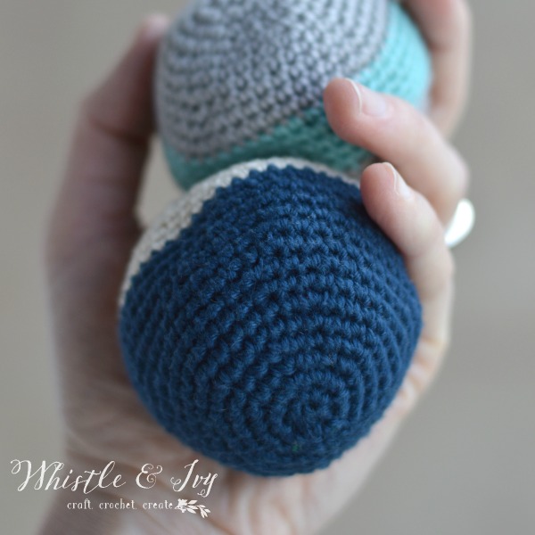 hand holding two crochet hacky sacks or foot bags