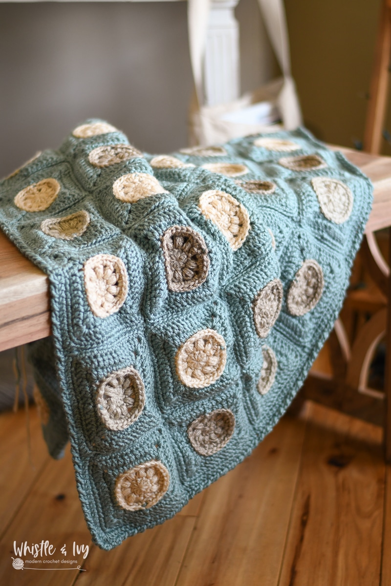 summer crocheting blanket featuring cream sand dollars on each square 